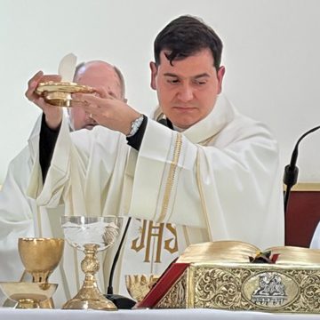 El padre John consagra la Eucaristía durante su primera misa del domingo.